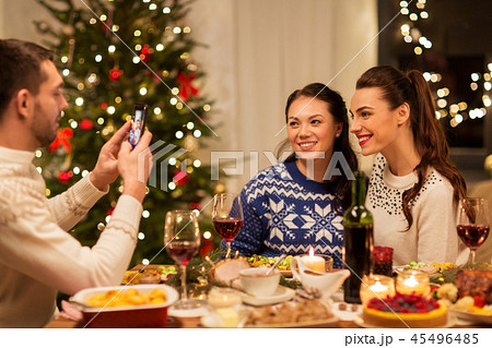 happy friends photographing at christmas dinner happy friends photographing at christmas dinner 45496485
