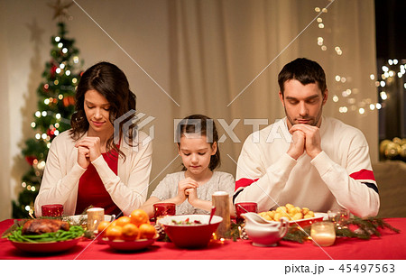 family praying before meal at christmas dinner 45497563