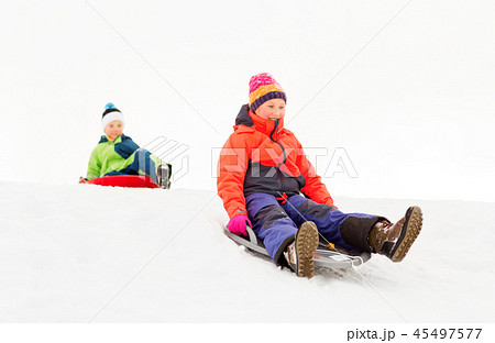 happy kids sliding on sleds down hill in winter 45497577