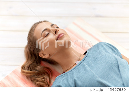 woman doing yoga corpse pose at studio 45497680