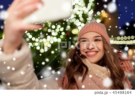 young woman taking selfie over christmas tree young woman taking selfie over christmas tree 45498164
