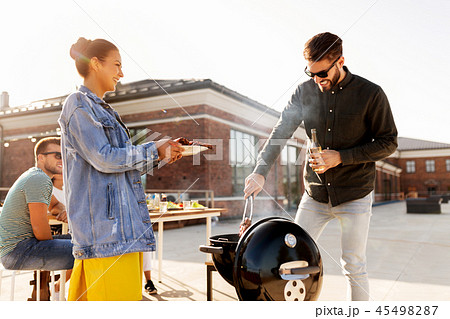friends cooking meat on bbq at rooftop party 45498287