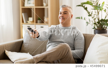 man with remote control watching tv at home 45499071