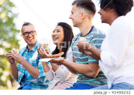 happy friends eating sandwiches and pizza outdoors happy friends eating sandwiches and pizza outdoors 45499232