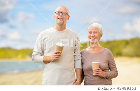 senior couple with takeaway coffee on beach senior couple with takeaway coffee on beach 45499353