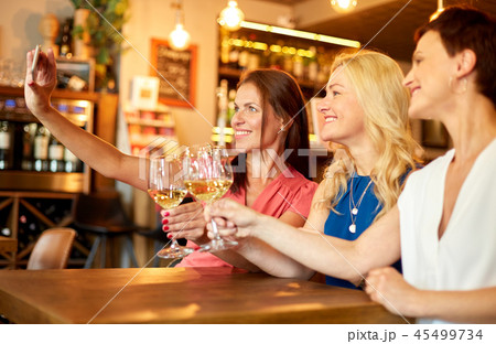 women taking selfie by smartphone at wine bar women taking selfie by smartphone at wine bar 45499734