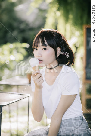 portrait of asian girl with white shirt and skirt eating ice cream in outdoor nature vintage film style 45500185