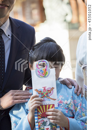 七五三イメージ　千歳飴の持ち手から覗き込む子供 45501052