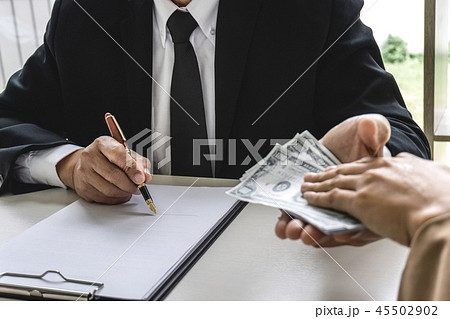 Business woman giving bribe money the form of dollar bills to ma 45502902