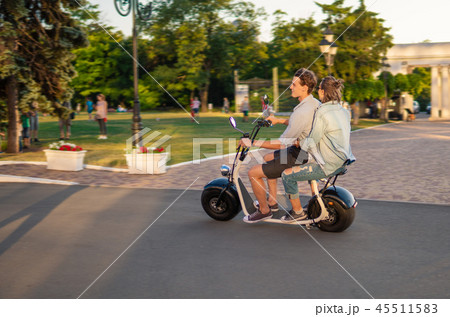 Lovely young happy couple driving electric bike 45511583