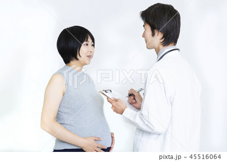 タンクトップの妊婦に問診する白衣の男性医師 産婦人科 妊娠 問診イメージの写真素材