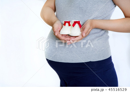 妊娠した大きなお腹の前に持つ新生児用の小さな靴下。妊娠,妊婦,臨月,望み,愛,幸福イメージ 45516529
