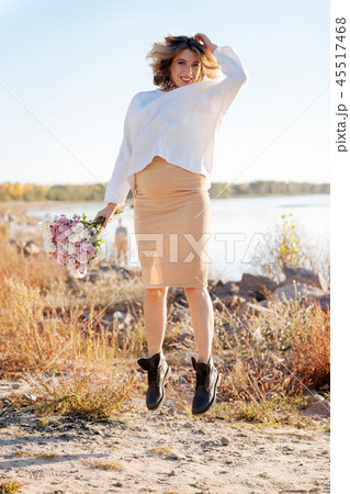 Pregnant woman happily jumping with the bunch of flowers Pregnant woman happily jumping with the bunch of flowers 45517468