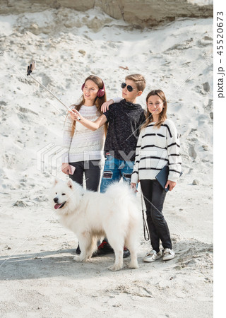 three friends with a doog breed samoyed makind selphie on a beach 45520673