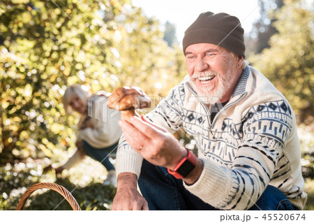 Pleasant cheerful aged man looking at the mushroom 45520674