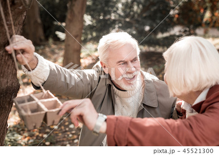 Happy aged couple feeding birds in the forest 45521300