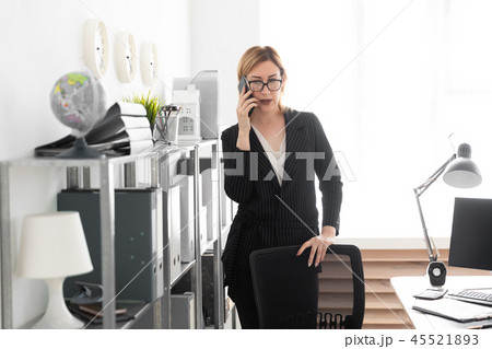 A young girl standing in the office and talking on the phone. 45521893