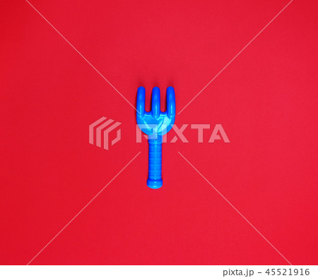 blue plastic baby rake on a red background 45521916