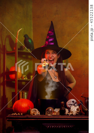 Photo of witch in black hat with hand outstretched with magic wand Photo of witch in black hat with hand outstretched with magic wand 45522138