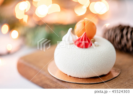Mini mousse pastry dessert covered with white velour on garland lamps bokeh background. Modern Mini mousse pastry dessert covered with white velour on garland lamps bokeh background. Modern 45524303