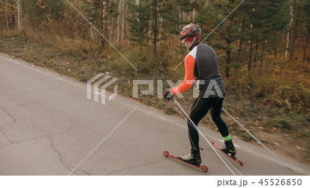 Training an athlete on the roller skaters. Biathlon ride on the roller skis with ski poles, in the 45526850