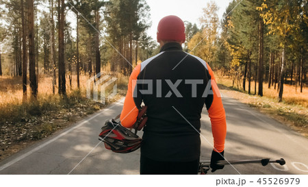 Training an athlete on the roller skaters. Biathlon ride on the roller skis with ski poles, in the 45526979