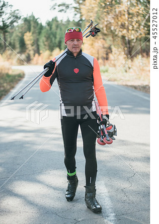 Training an athlete on the roller skaters. Biathlon ride on the roller skis with ski poles, in the Training an athlete on the roller skaters. Biathlon ride on the roller skis with ski poles, in the 45527012