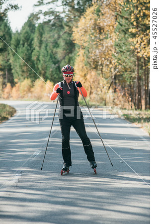 Training an athlete on the roller skaters. Biathlon ride on the roller skis with ski poles, in the 45527026