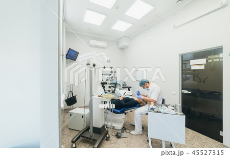 Doctor used microscope. Dentist is treating patient in modern dental office. Operation is carried Doctor used microscope. Dentist is treating patient in modern dental office. Operation is carried 45527315