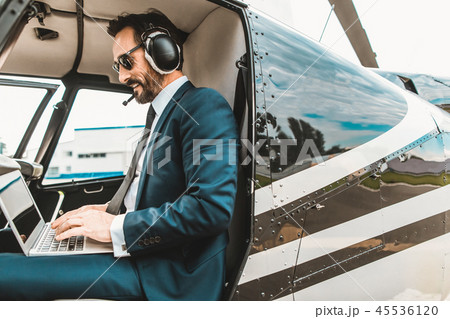 Happy man sitting in the helicopter cabin and using the laptop 45536120