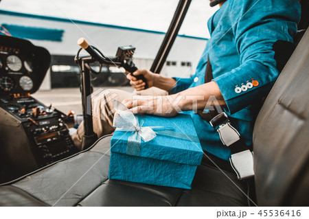 Careful man touching the present while sitting in the helicopter cabin Careful man touching the present while sitting in the helicopter cabin 45536416