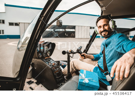 Bearded pilot smiling and looking at you from helicopter cabin 45536417