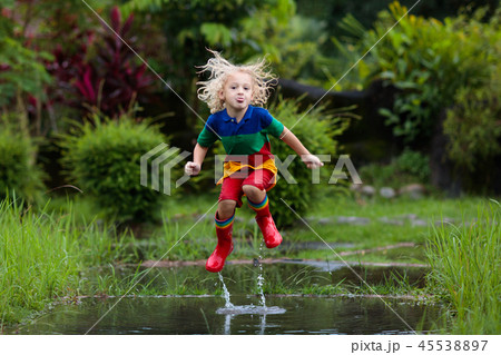 Kid with umbrella playing in summer rain. Kid with umbrella playing in summer rain. 45538897