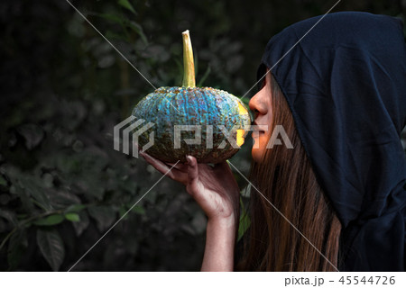 Female wizard kissing pumpkin lantern. Female costume in black c 45544726