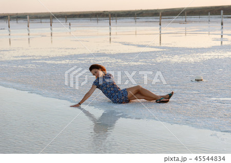 happy girl enjoying the sunset, touches water of a salt lake sitting on crystals happy girl enjoying the sunset, touches water of a salt lake sitting on crystals 45544834