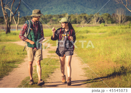 Two people walking on path in meadow field. Male and female trav Two people walking on path in meadow field. Male and female trav 45545073