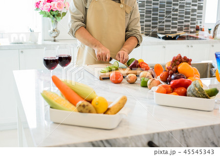 Man cooking and slicing vegetable in the kitchen Man cooking and slicing vegetable in the kitchen 45545343