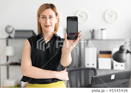 Young girl standing in the office and shows the phone screen. 45545436
