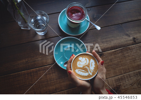 Female hands holding a Cup of coffee an dessert on wooden table 45546853