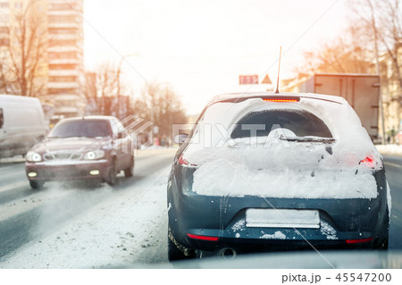 Cars moving on city street on slippery snowy road in winter. Vehicles covered with snow drift after Cars moving on city street on slippery snowy road in winter. Vehicles covered with snow drift after 45547200