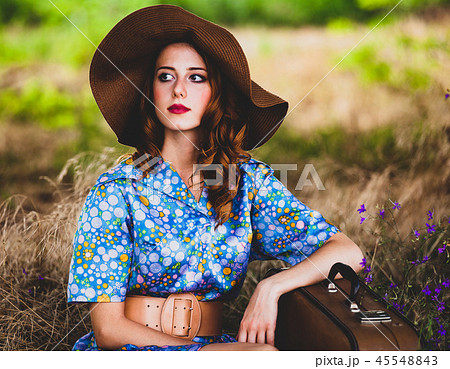 Young redhead girl in hat and dress with suitcase 45548843