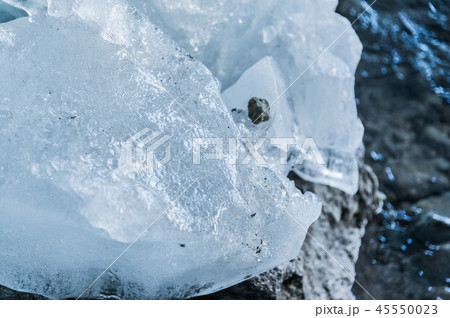 Close-up pieces of ice showered in the ice grotto of a glacier. The destruction of the glacier Close-up pieces of ice showered in the ice grotto of a glacier. The destruction of the glacier 45550023