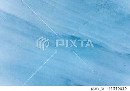 Close-up blurred wall of a centuries-old glacier with a structure of stripes and bubbles. Ice blue 45550030