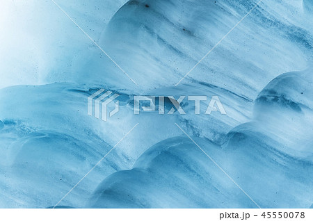 Close-up wall of a centuries-old glacier with a structure of stripes and bubbles. Ice blue light 45550078