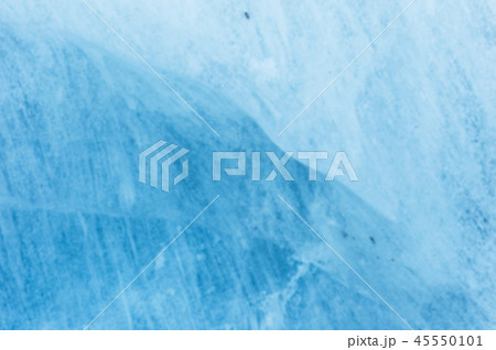Close-up blurred wall of a centuries-old glacier with a structure of stripes and bubbles. Ice blue Close-up blurred wall of a centuries-old glacier with a structure of stripes and bubbles. Ice blue 45550101