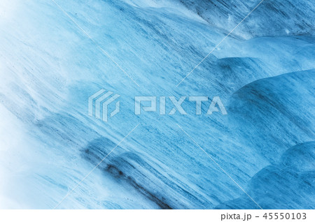 Close-up wall of a centuries-old glacier with a structure of stripes and bubbles. Ice blue light 45550103
