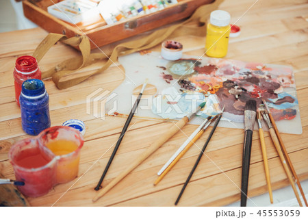 The artist's palette. Colored oil paints over a pallete on a table. The artist's palette. Colored oil paints over a pallete on a table. 45553059