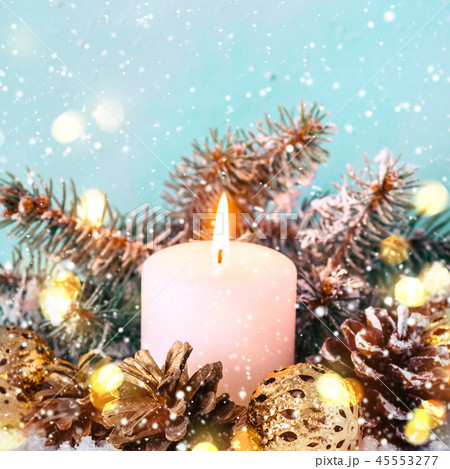 Burning candle decorated with natural cones On a blue background. Bokeh 45553277