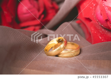 Gold wedding rings with red roses background Gold wedding rings with red roses background 45553307