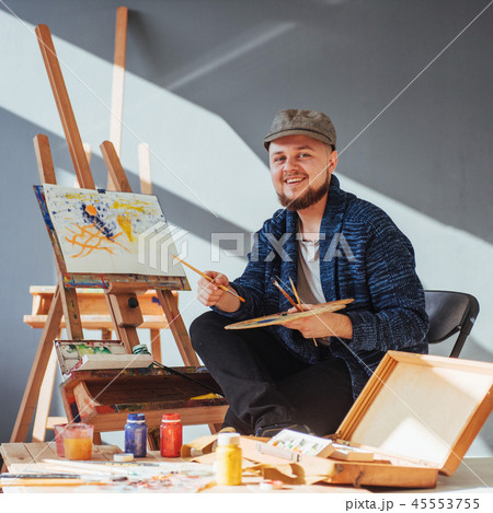 Designed by artist man finishing his masterpiece holds a brush in hand. 45553755
